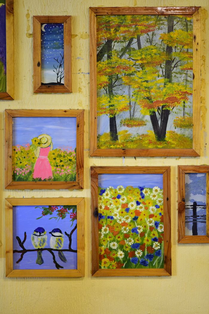 Mastering the First Impression: Your intriguing post title goes here Vibrant framed artwork depicting nature scenes and flowers on a rustic wall.